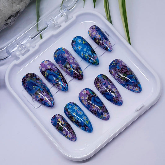 Set of blue floral nail art designs in a clear case on a light background
