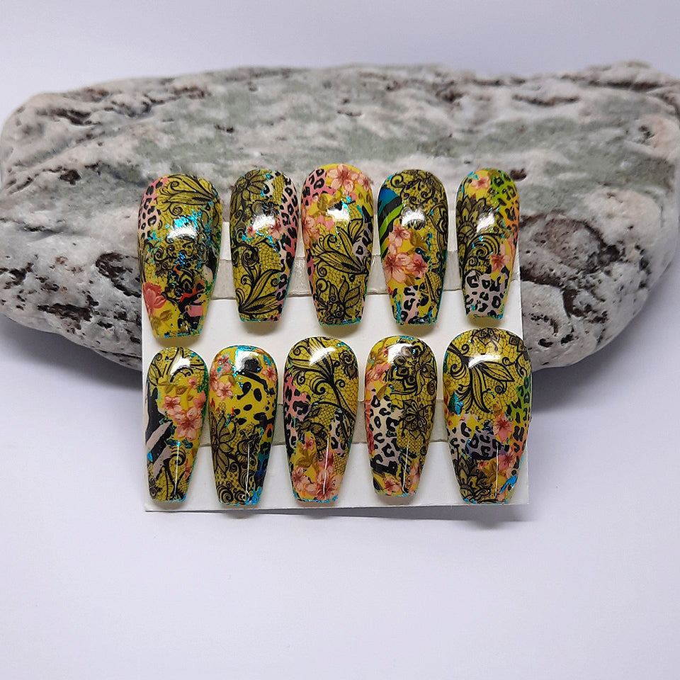 yellow hand made press on nails with an abstract design of animal print, black lace and flowers. Pictured in medium coffin.