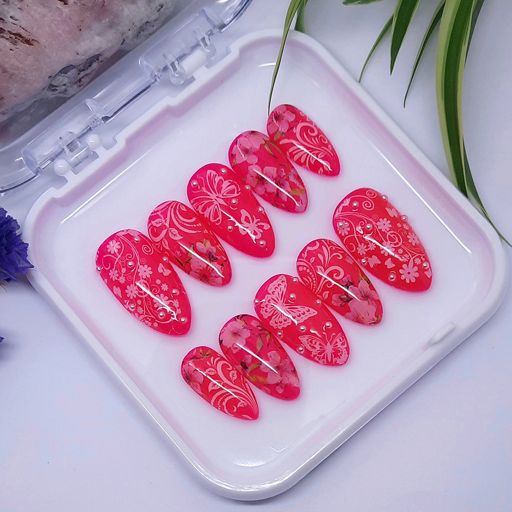Bright and pretty press on nails. Pink gel polish with flowers and butterflies, finished off with little white pearls.