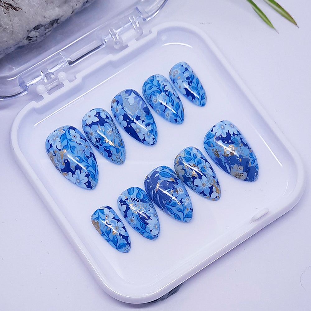 Set of blue floral nail designs in a clear plastic case on a light background