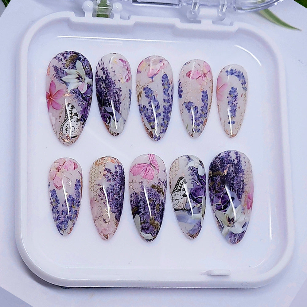 Set of press-on nails with floral and butterfly designs on a white tray.