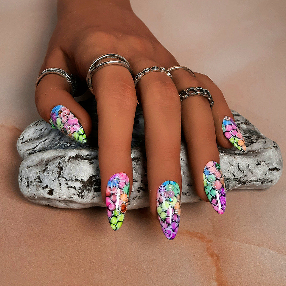 beautiful almond press on nails with a bright colourful dot design, covered in white swirly vones,and finished with gems and pearls