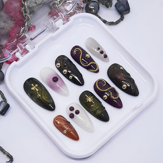 Set of artistic nail art designs on a white tray with decorative elements.