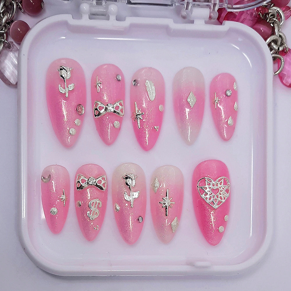 A pretty semi-sheer sparkly pink set of press on nails with silver 3d nail art, including roses, bow and hearts.