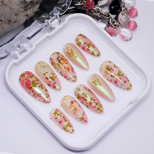 A set of press on nails with floral patterns and shimmering effects, displayed in a clear plastic case.