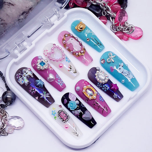Set of decorative false nails with various designs on a white tray.