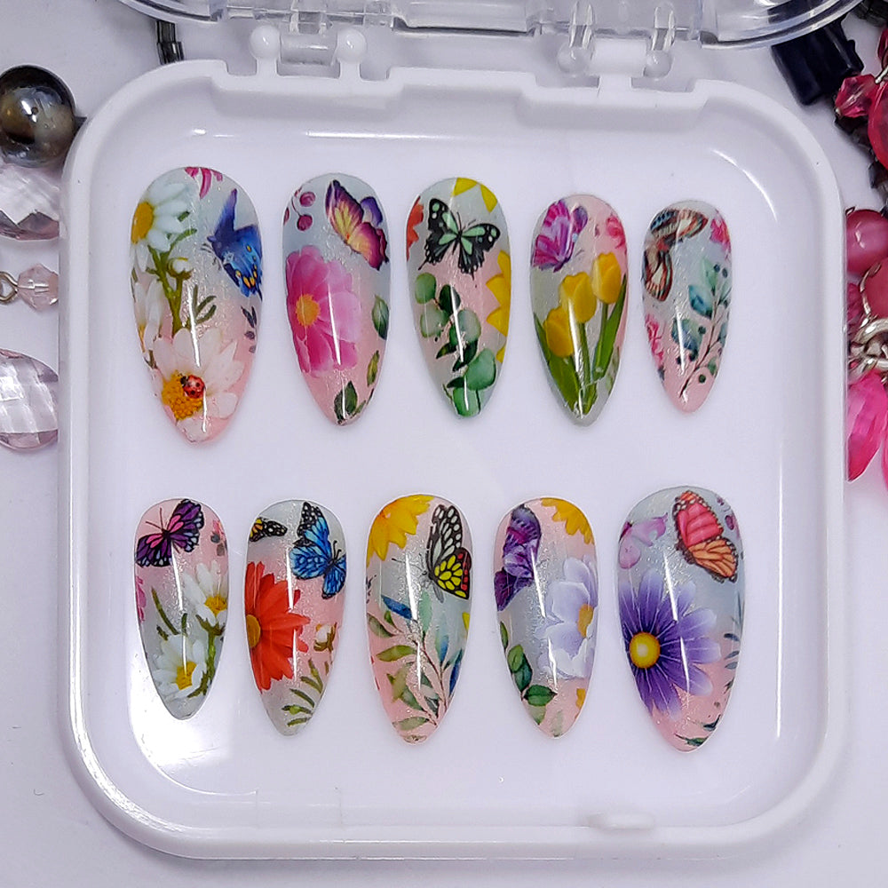 Gorgeous press on nails in subtle shimmering pink and blue, with brightly coloured flowers and butterflies. Finished in gloss top coat.