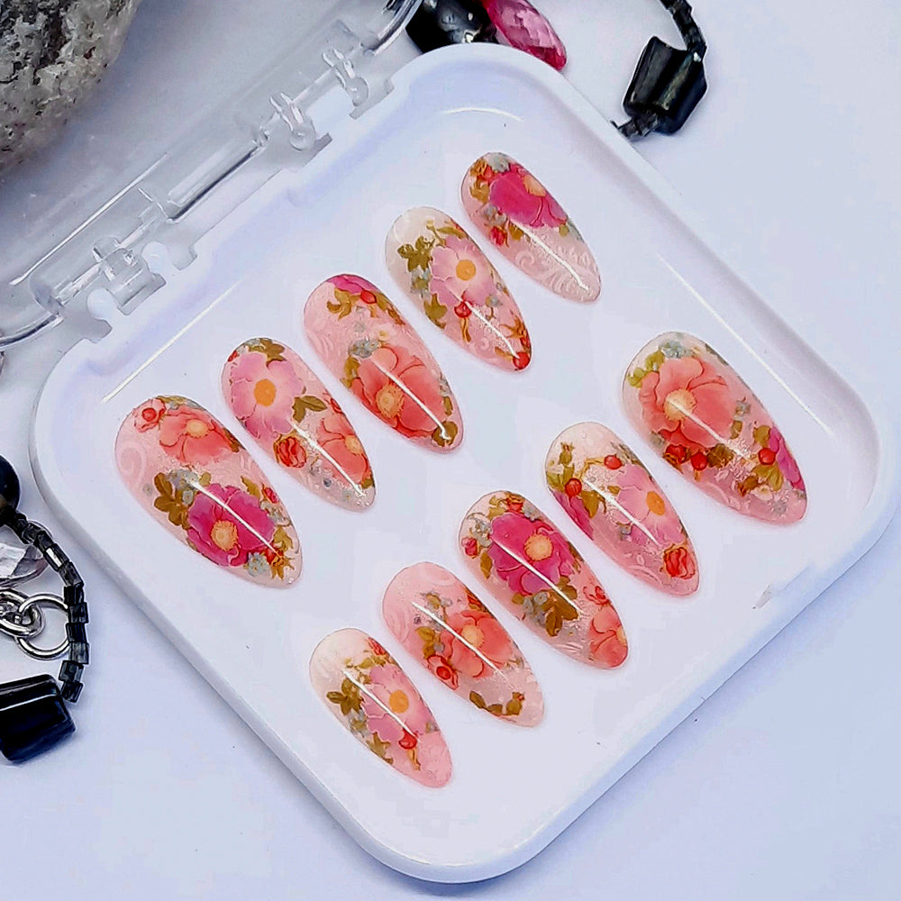 Beautiful press on nails in soft and subtle shimmering pink and orange, with beautiful roses in shades of pink. Finished in gloss top coat.