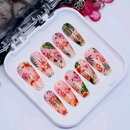 Very beautiful shimmering semi-sheer press on nails in soft orange and pink decorated with tropical flowers, leaves, and flamingos. Finished in gloss top coat.