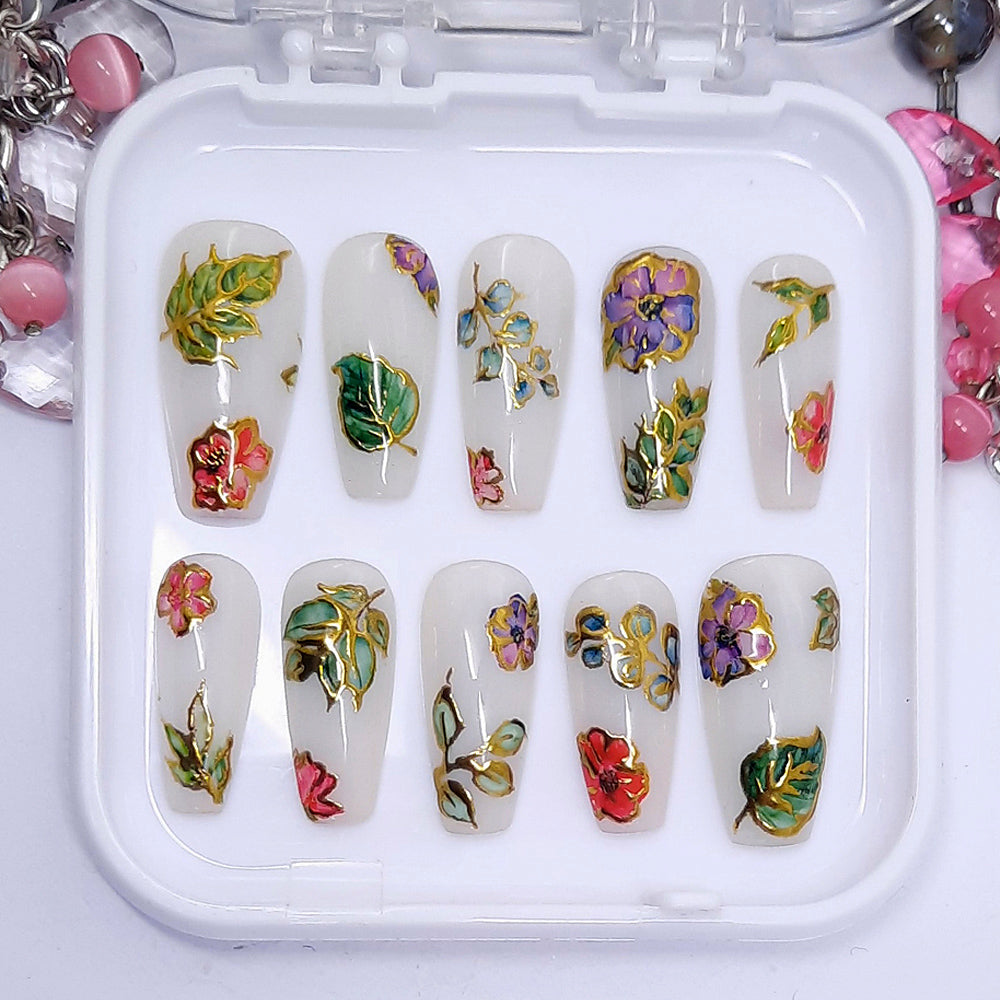 Very beautiful and unique press on nails in milky white with pink and purple flowers, leaves, and gold chrome. Finished in gloss top coat.