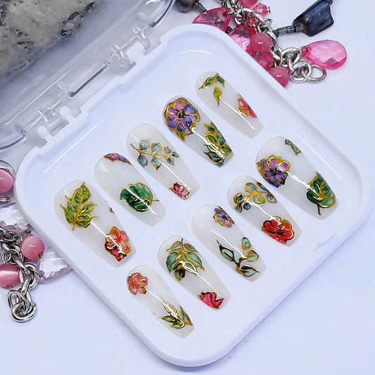 Very beautiful and unique press on nails in milky white with pink and purple flowers, leaves, and gold chrome. Finished in gloss top coat.