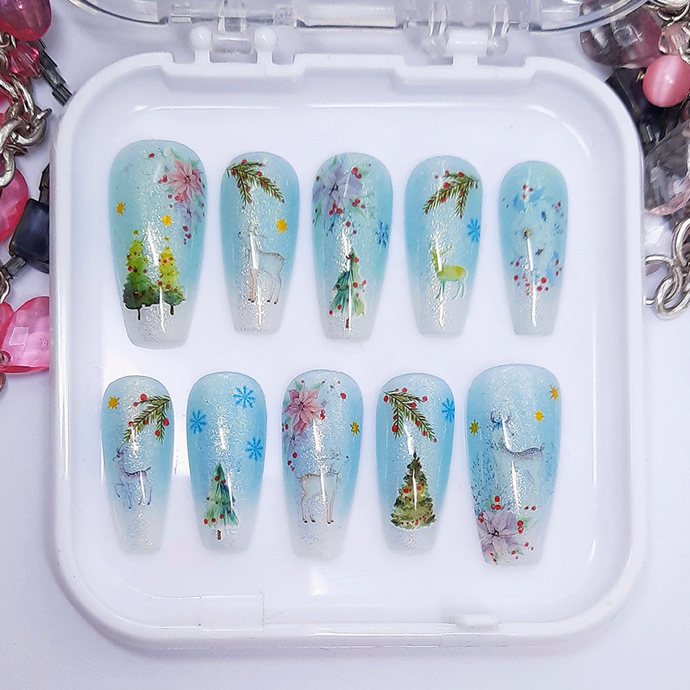 A set of press on nails in blue and white with a Christmas themed design, displayed in a white tray on a white background.