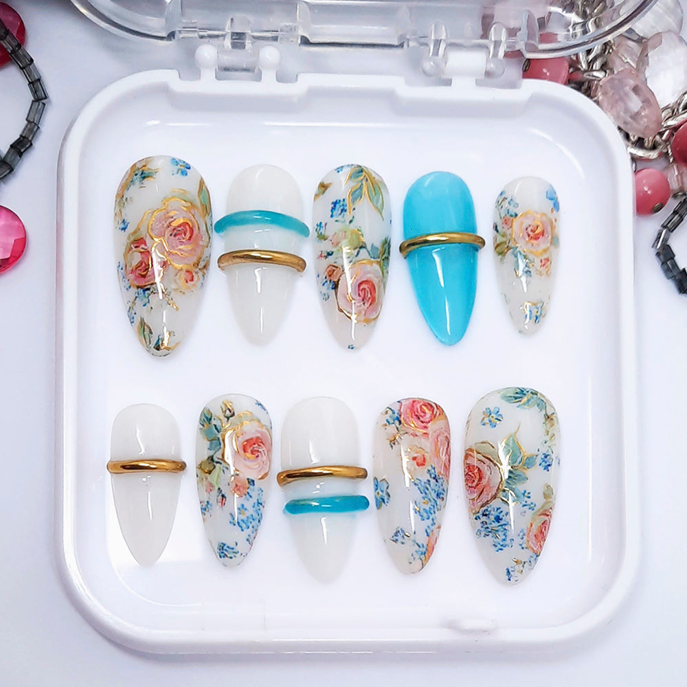 Set of decorative nail art designs in a white case with floral and blue patterns.