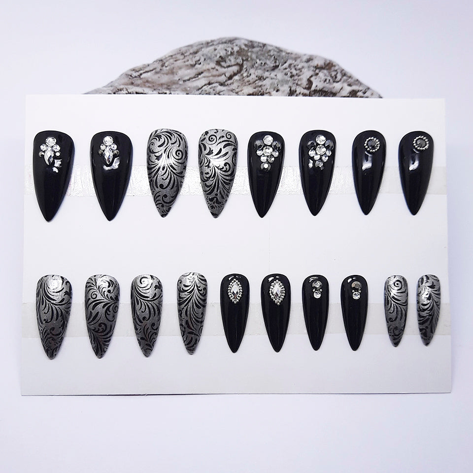 Set of black and silver nail art designs on a white card with a white background.