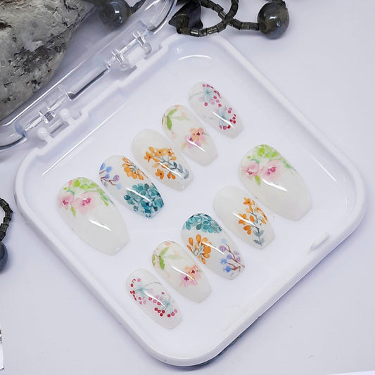 A set of white press on nails with a floral design in a tray on a white background.