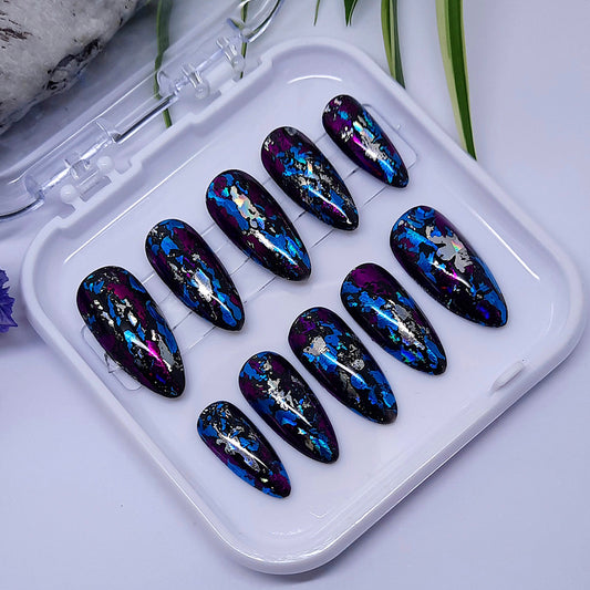 Gorgeous black nails with foils in blue, purple, and silver. Finished with a glossy top coat.

Please select your size, shape &amp; length. Medium Almond is pictured.