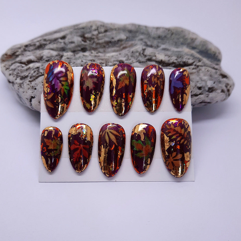 autumn themed press on nails in a deep sparkly purple gel, with holo foils and leaves
