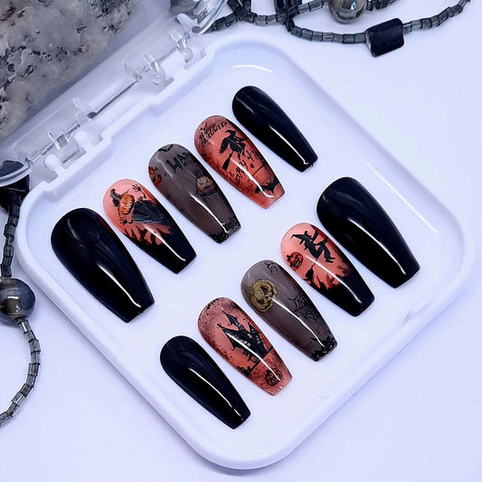 A set of halloween themed press on nails with designs including witches and pumpkins.