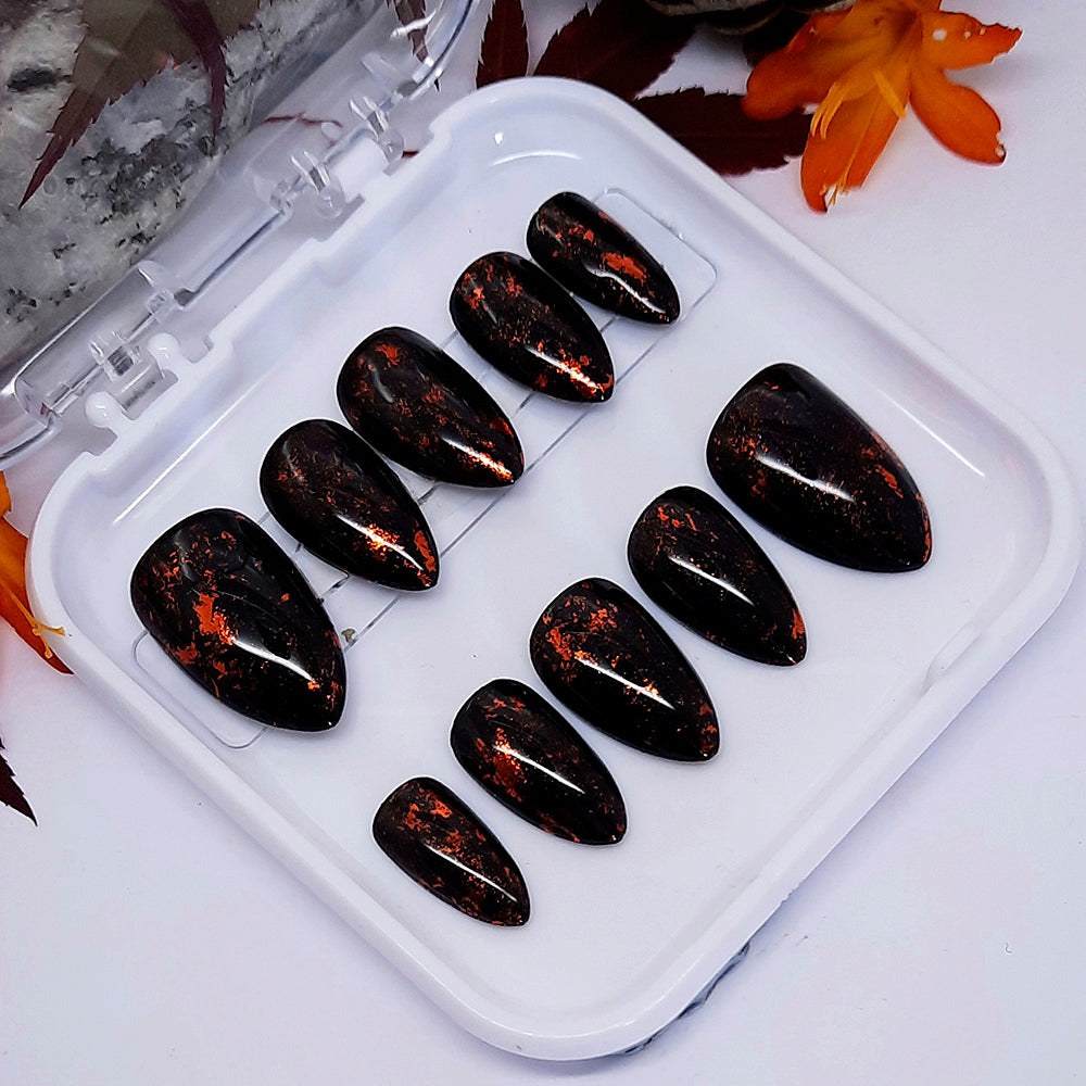 Set of black glossy hand made false nails with flecks of gold.