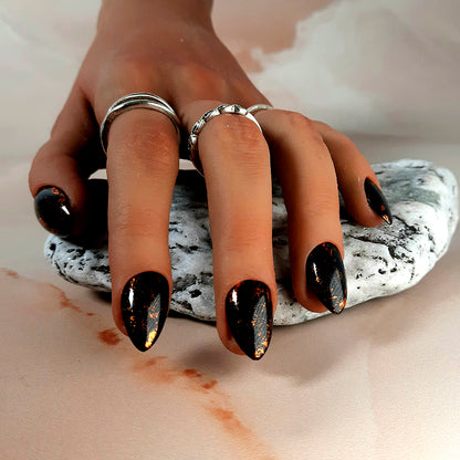 shiny black extra short almond press on nails with flecks of burnt orange foil. Hand made by moona nails.