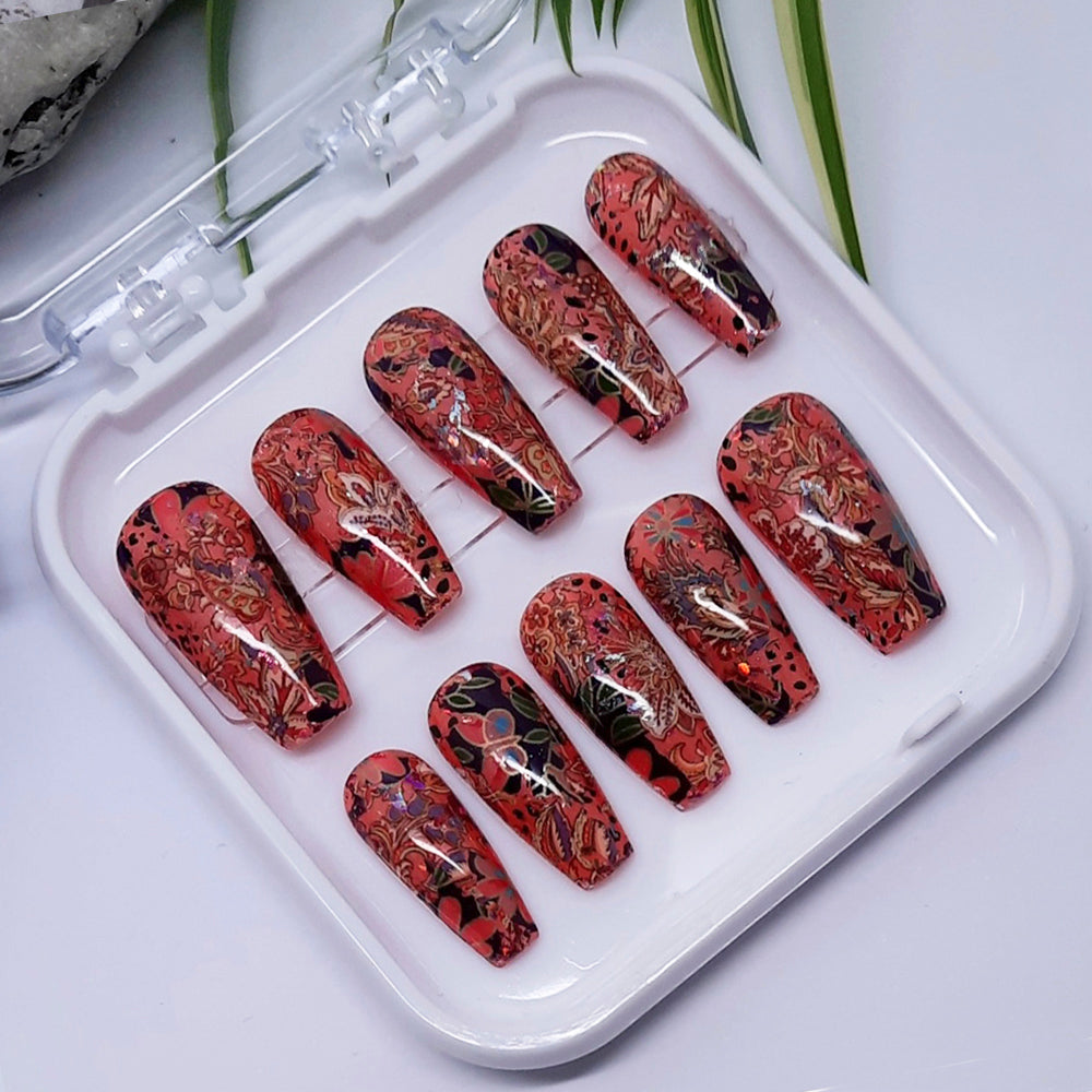 Set of red and black patterned false nails in a clear plastic case on a white surface.