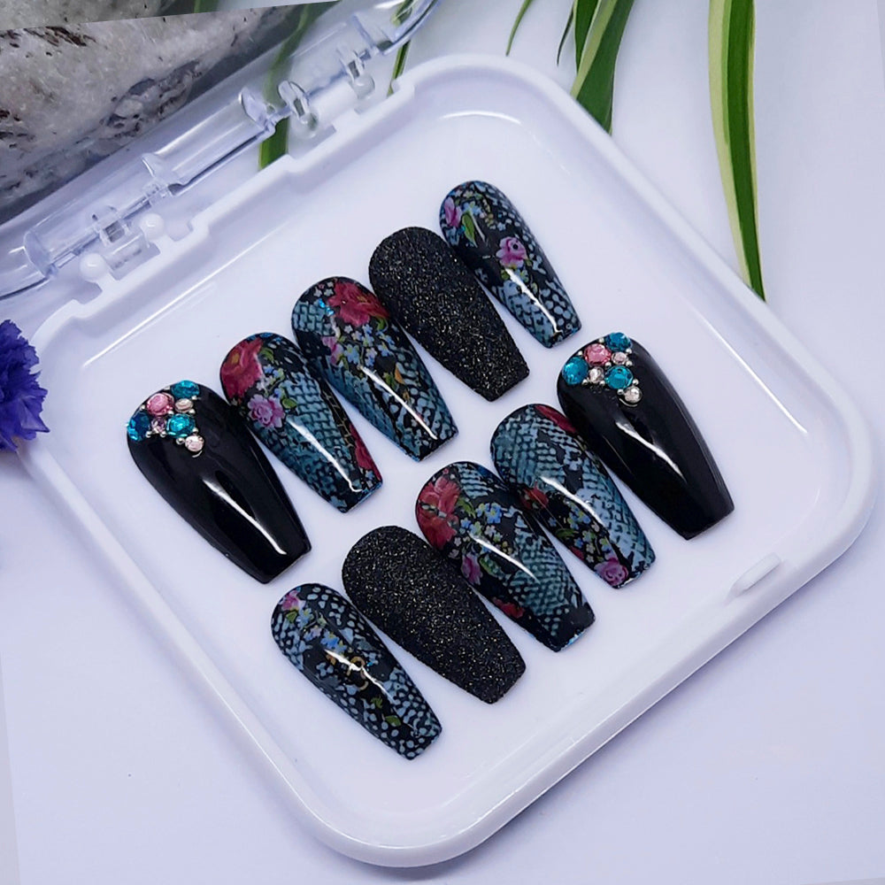 Set of black, snakeskin and floral nail designs on a white tray with a white background
