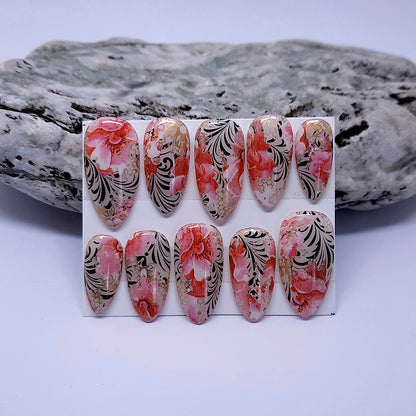 A beautiful set of hand made almond press on nails with a design of flowers and black vines.