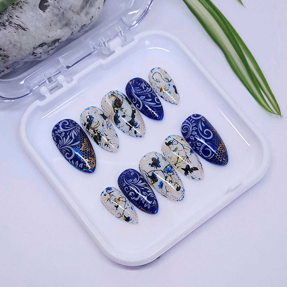 Beautiful almond hand made press on nails in dark blue and milky white, with flowers, vines, and gold mesh.