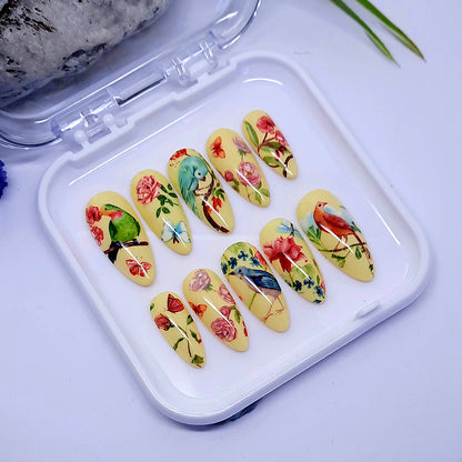 beautiful pastel yellow almond hand made press on nails with a design of flowers, butterflies and birds.