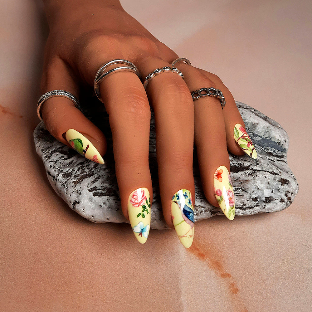 beautiful pastel yellow almond hand made press on nails with a design of flowers, butterflies and birds.