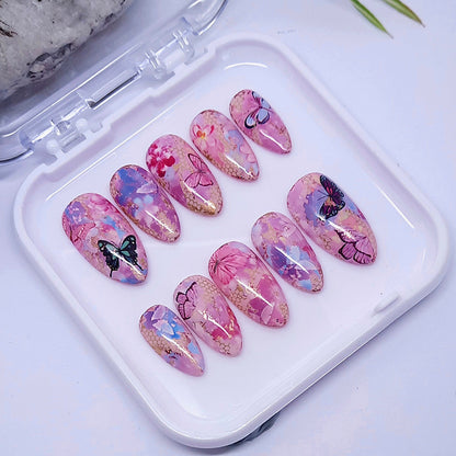 Set of pink and purple butterfly-themed nail art designs in a white case.