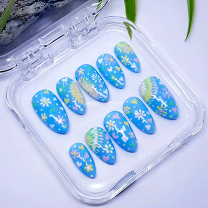 Decorative blue nail art with floral designs in a clear plastic case.