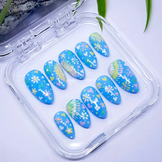 Decorative blue nail art with floral designs in a clear plastic case.
