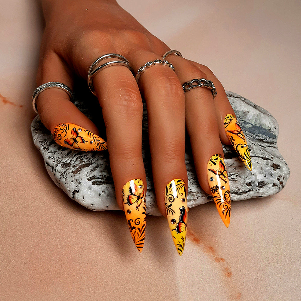 hand made long stiletto press on nails in an orange and yellow ombre, with orange butterflies, black vines and gems.