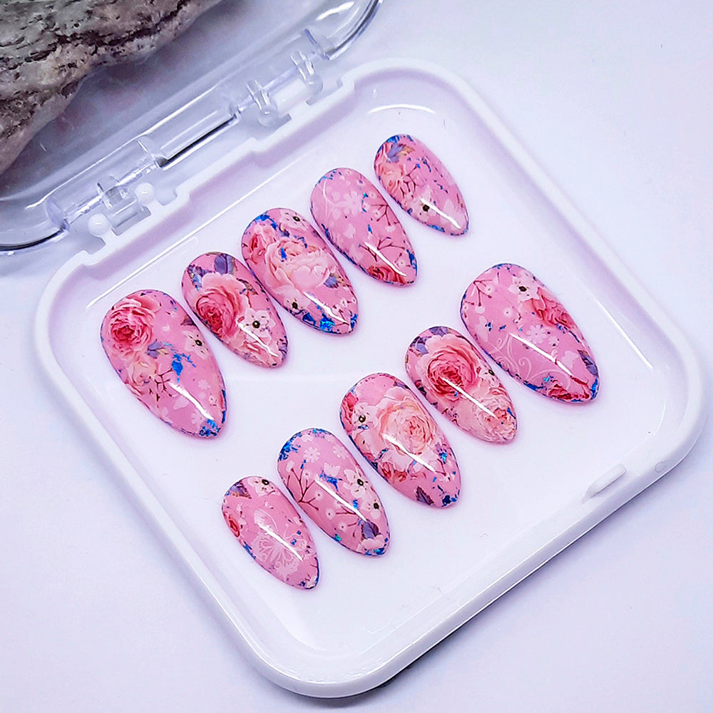 Set of pink floral nail art designs in a clear case on a light background
