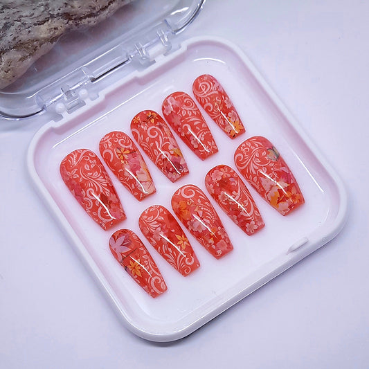 beautiful hand made press on nails in a coral gel polish, with flowers and white vines