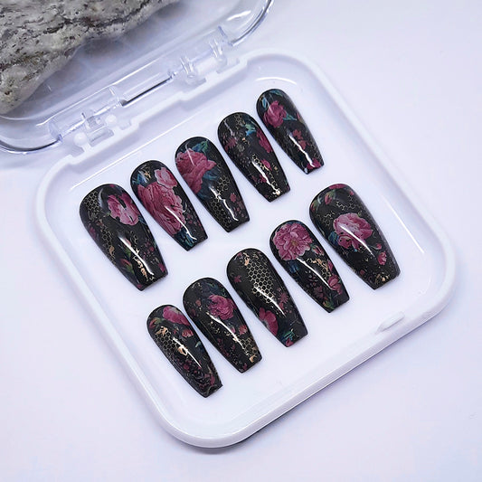 Set of black floral nail art designs in a clear plastic case on a light gray background
