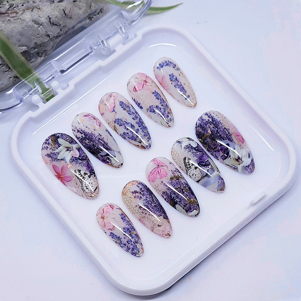 Decorative false nails with floral designs on a white tray.