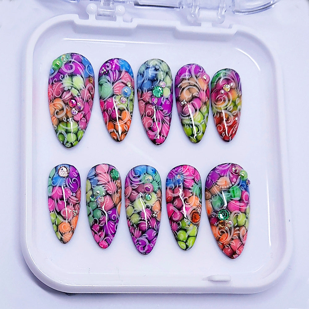 A set of colourful press on nails decorated with some 3d nail art.