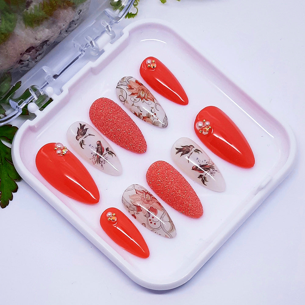 A set of nail art designs in red and white with flowers, birds, glitter and some 3d elements. Displayed in a white tray.