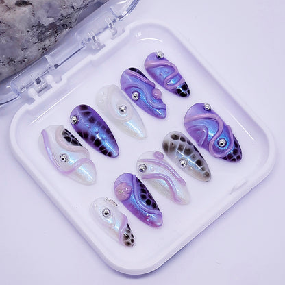 Set of purple and white nail art designs in a clear case on a light gray background