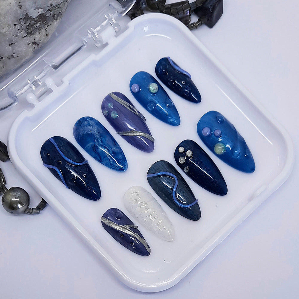 Set of blues and white nail art designs in a white case on a light grey background