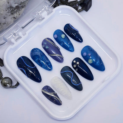 Set of blues and white nail art designs in a white case on a light grey background