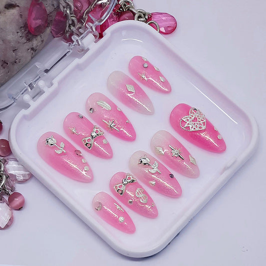 A pretty semi-sheer sparkly pink set of press on nails with silver 3d nail art, including roses, bow and hearts.