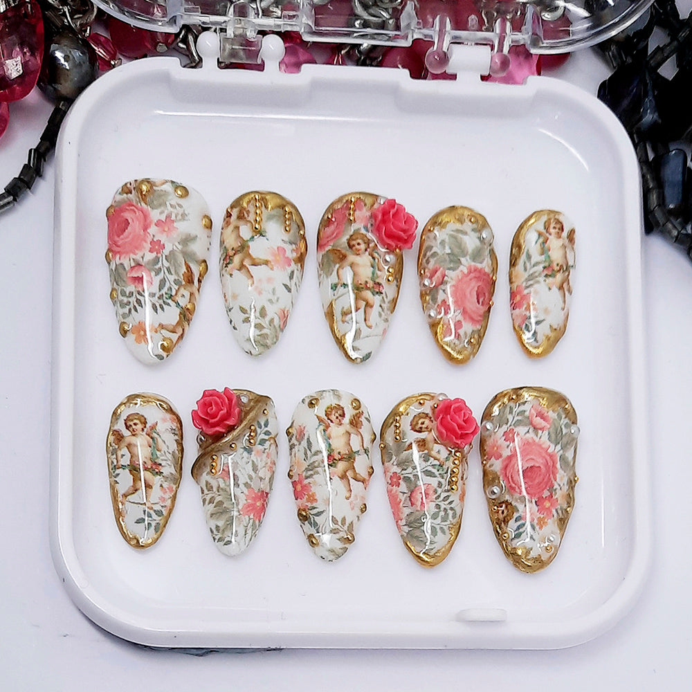Decorative nail art designs with cherubs and roses on a white tray.