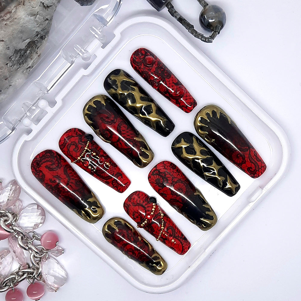 A beautiful red and black set of press on nails with black lace, gold chrome, gold caviar beads, red gems and black studs.