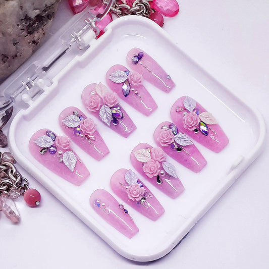 Pink nail art designs with floral and leaf decorations on a white tray.