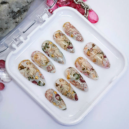 Decorative press on nail set with designs of angels, cupids and roses with some 3d gold nail art.