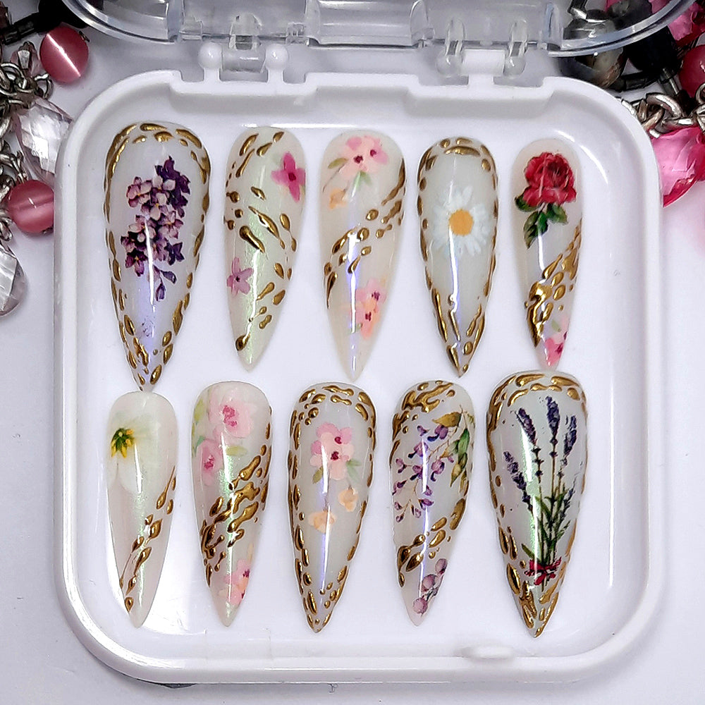 A stunning set of press on nails. In a shimmering milky white with flowers and gold chrome.