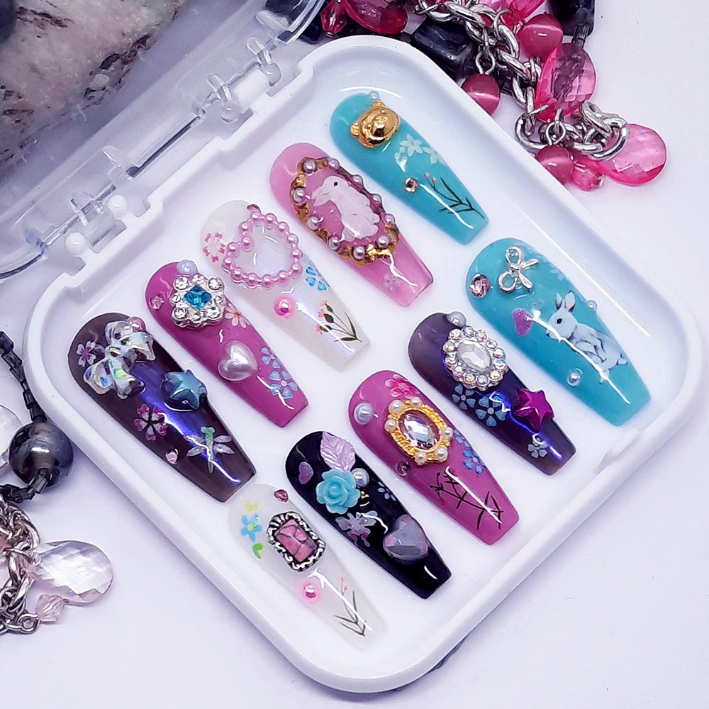 Set of decorative false nails with various designs on a white tray.